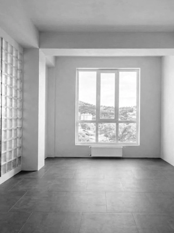 Minimalist empty interior with gray floor tiles, a large window, and a glass block partition wall