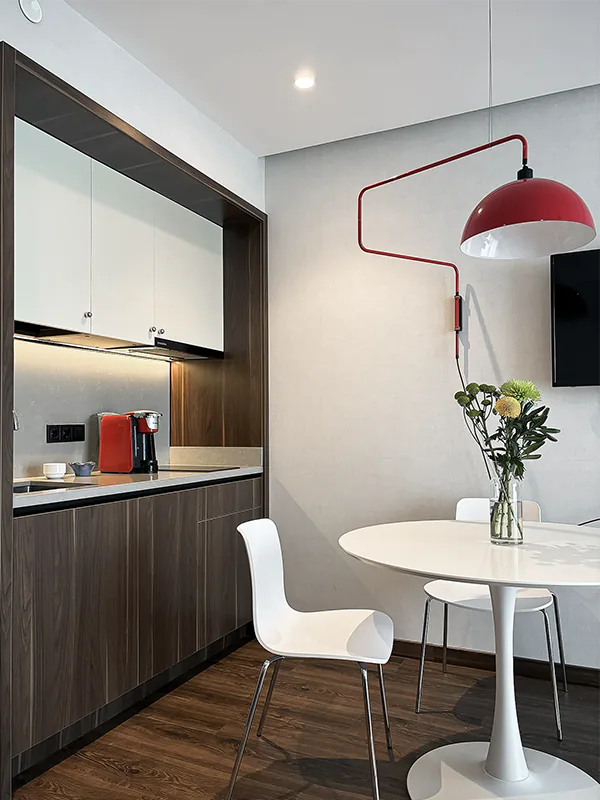 Private apartment interior in Batumi with compact built-in kitchen, dining area, dark wood cabinetry and modern finishes
