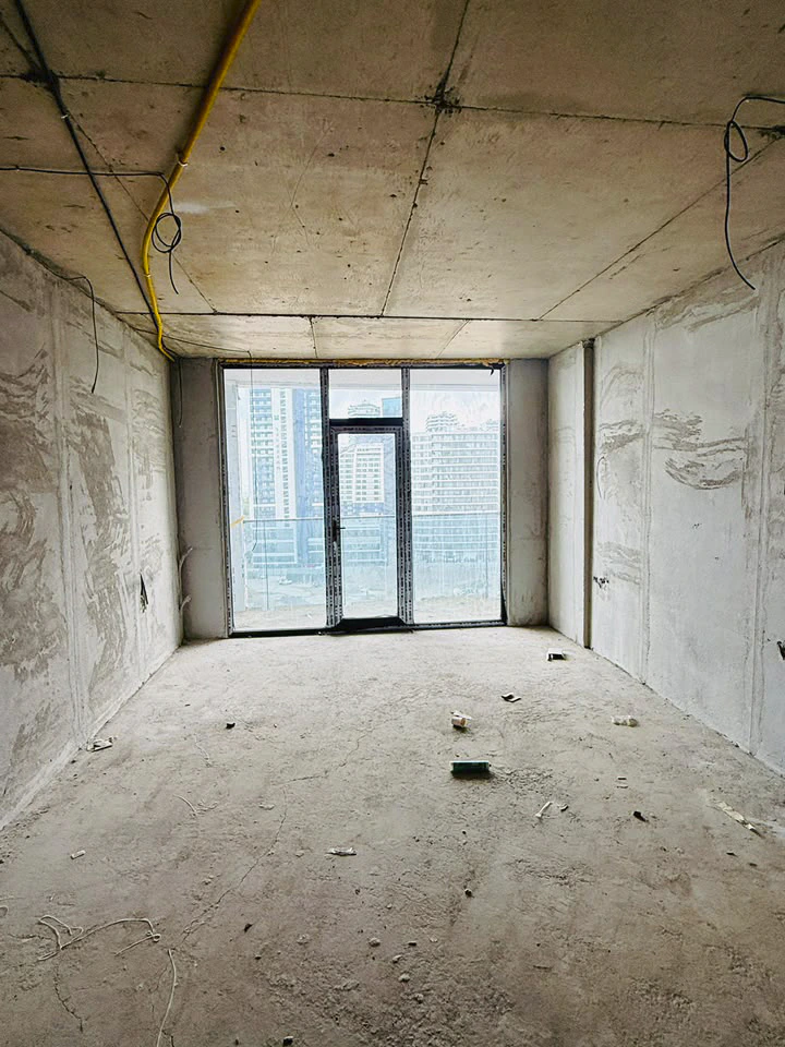 Unfinished studio with plastered walls and full-height glazing opening onto the balcony