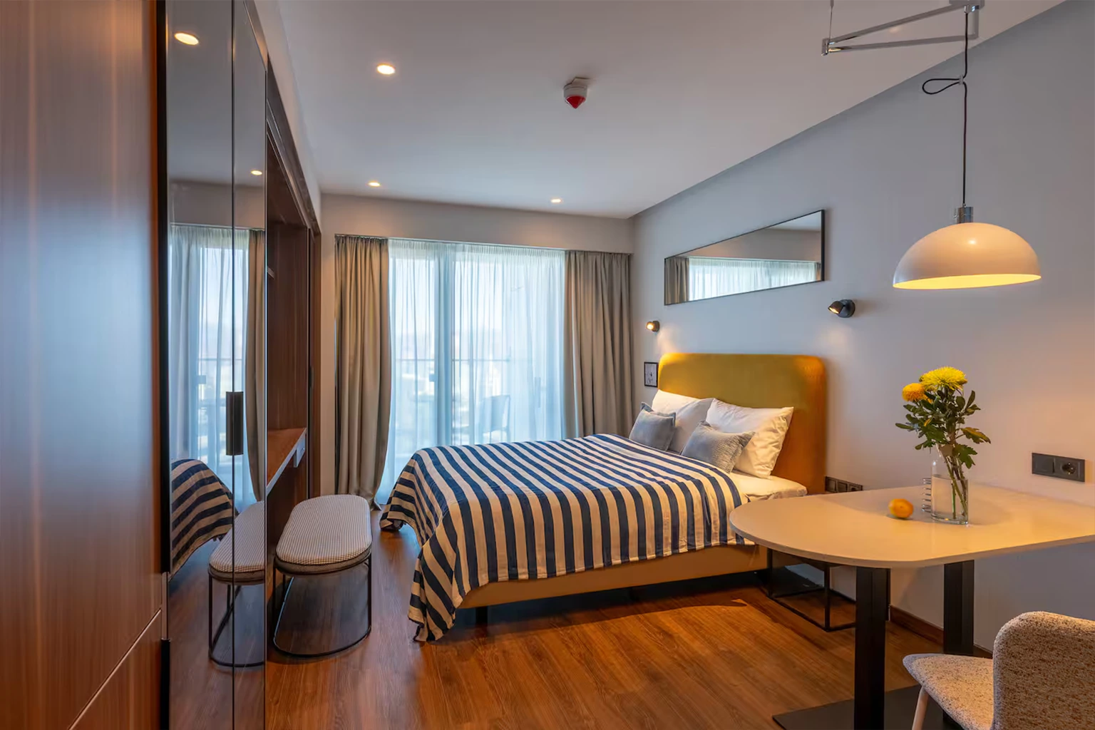 Modern studio bedroom with dining area and balcony windows